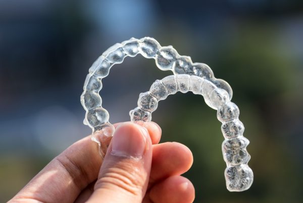 A pair of Invisalign held up in front of the camera