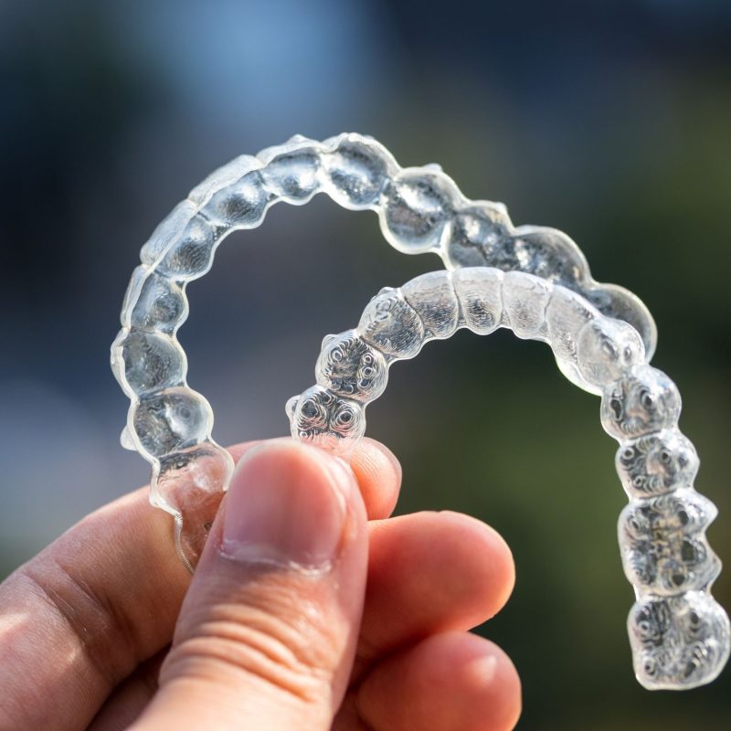 A pair of Invisalign held up in front of the camera