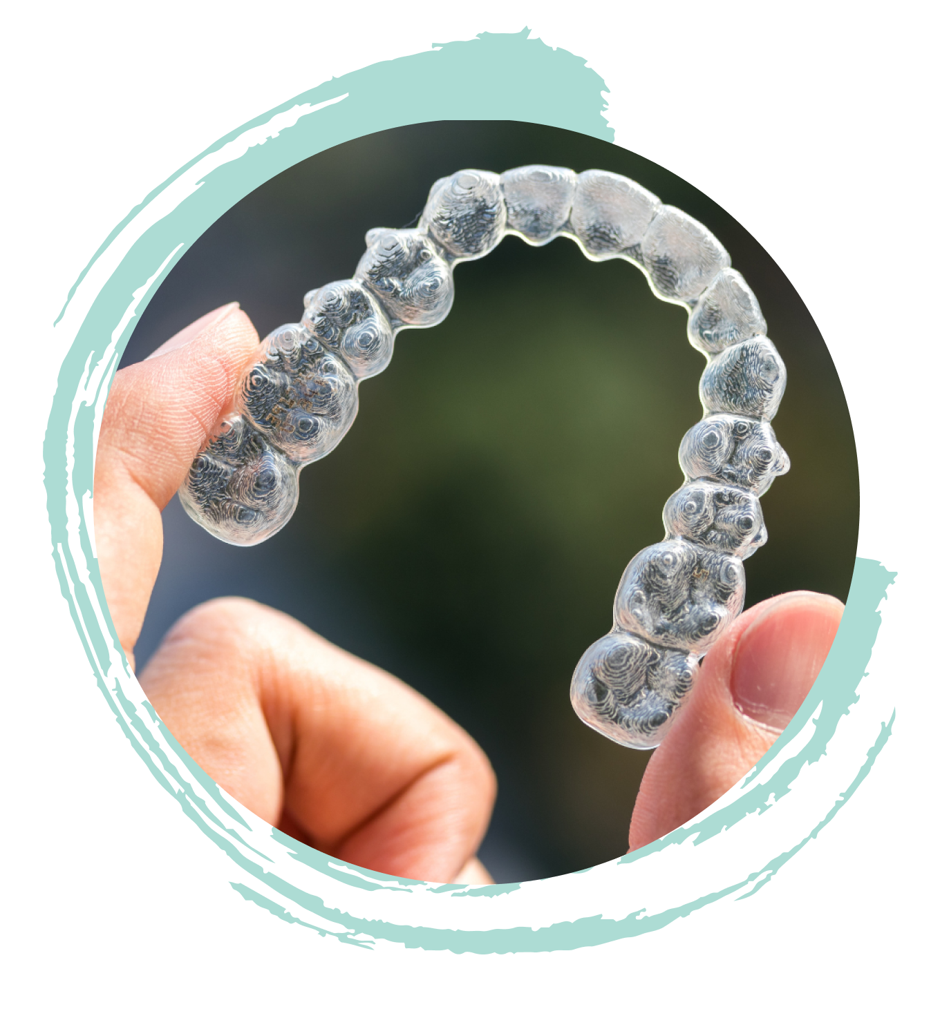 Clear retainer being held by two fingers.