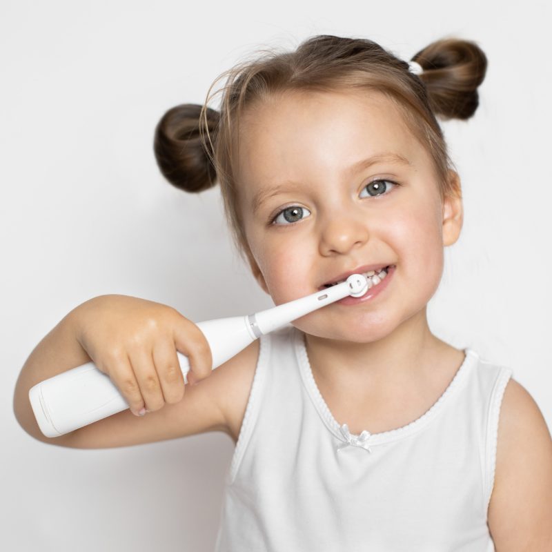 Young girl using electric toothbrush