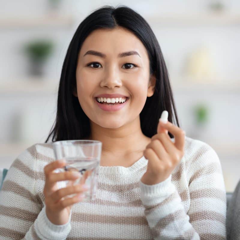 Woman holding a multivitamin and glass of water