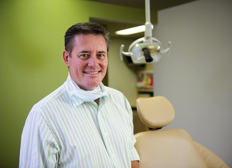 Doctor smiling in front of dentist's chair
