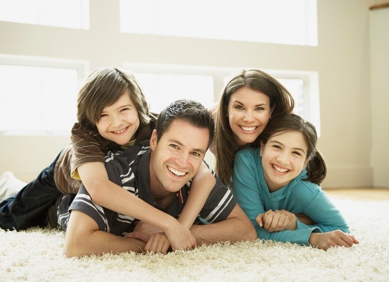Smiling family of four on white carpet