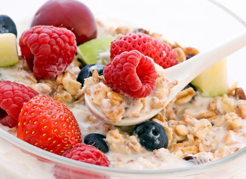 Spoonful of muesli in a bowl of cereal with berries