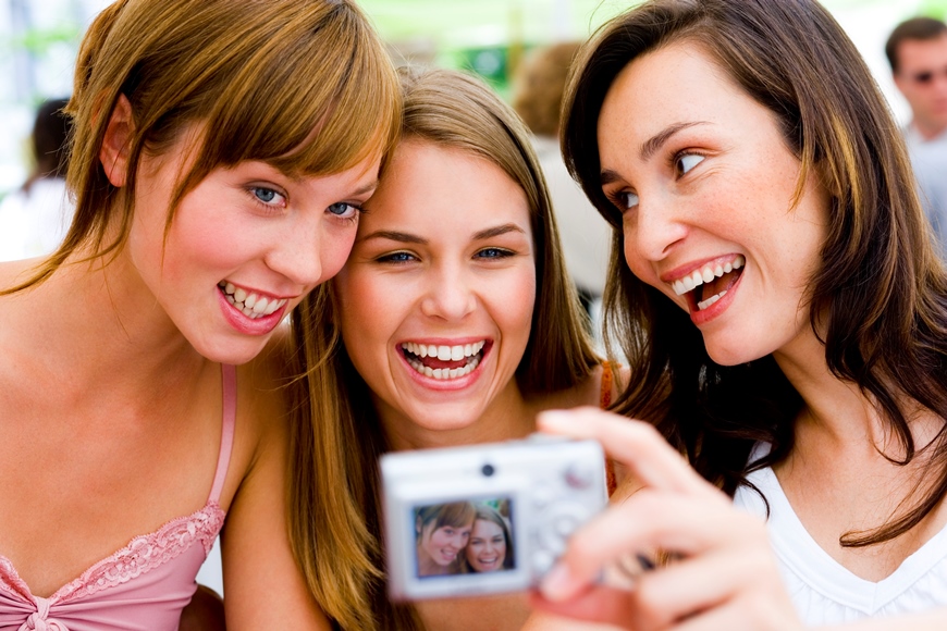 3 female friends smiling and talking a selfie to capture the moment. camera