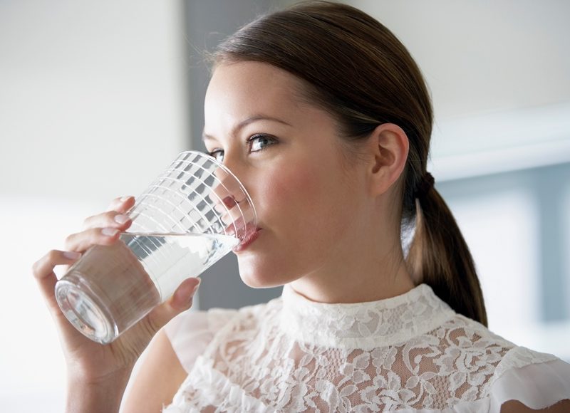 Woman drinking water from a clear glass